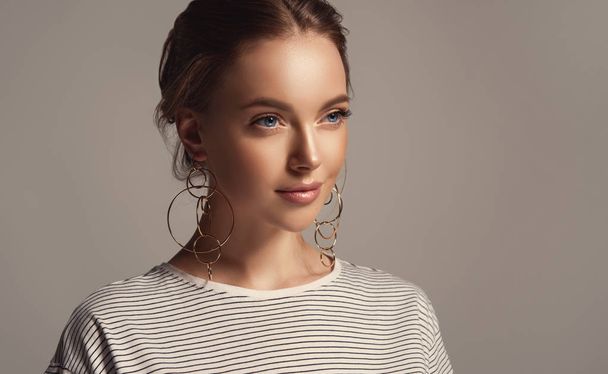 Beautiful girl in a striped T-shirt. Fashionable and stylish women's clothing . Fashion look , beauty and style. Young woman in trendy jewelry earrings rings. - Photo, Image