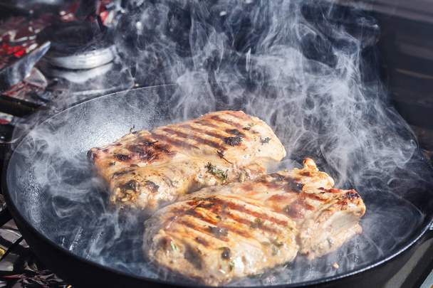 smoke and steam rise from a pork steak on grill pan  - Photo, Image