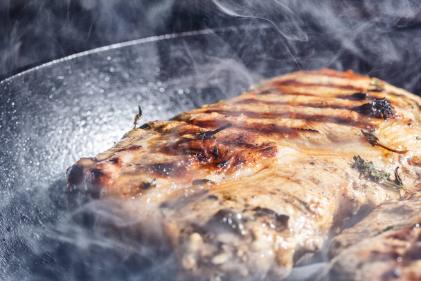 fumaça e vapor sobem de um bife de porco na panela da grelha
  - Foto, Imagem