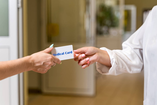 Kobieta w średnim wieku lekarz w białej szatę akceptując kartę medyczną - Zdjęcie, obraz