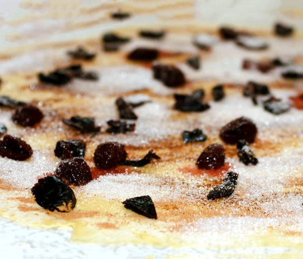 Une feuille de pâte saupoudrée de morceaux de cannelle, de sucre et de pruneaux. texture
. - Photo, image