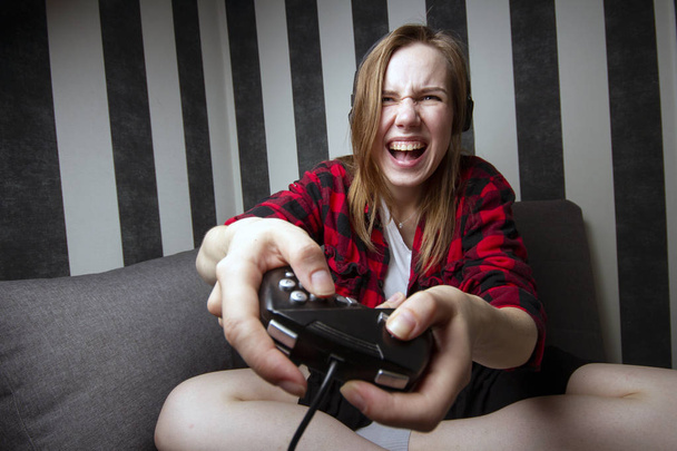 Jovem menina agressiva joga jogos de computador no joystick à noite no quarto, ela grita no console
 - Foto, Imagem