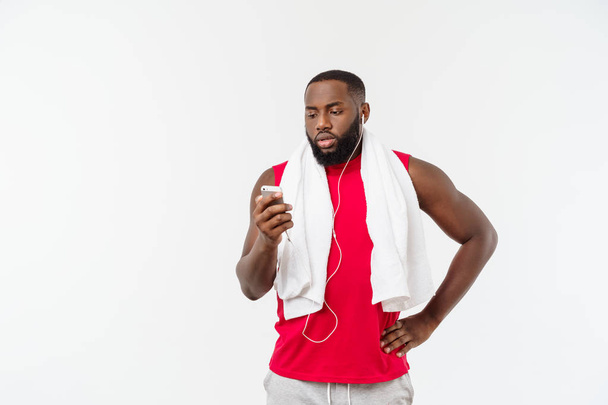 Bonito homem afro-americano ouvindo música em seu dispositivo móvel após o exercício esportivo
. - Foto, Imagem
