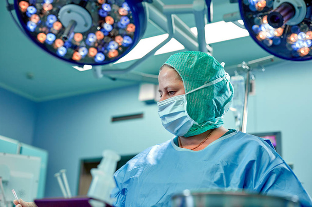 Cirujano plástico femenino, disparado mientras trabajaba en el quirófano. Emociones reales, estilo de vida, operación real
. - Foto, imagen