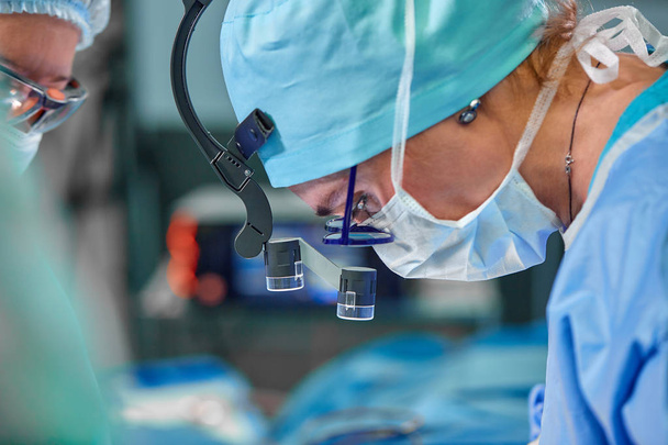A surgeons team in uniform performs an operation on a patient at a cardiac surgery clinic. Modern medicine, a professional team of surgeons, health. - Photo, Image