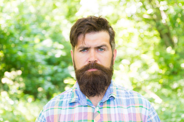 Handsome lumberjack. Man beard and mustache in summer forest. Hike and travel. Summer vacation concept. Man bearded hipster green trees background. Guy relax in summer nature. United with environment - Fotoğraf, Görsel
