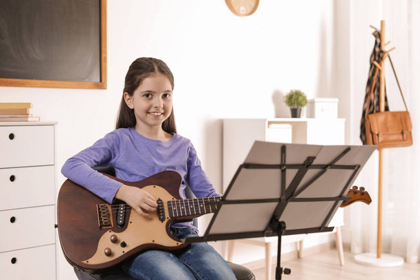 Little girl playing guitar at music lesson. Learning notes - Photo, image
