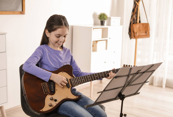 Little girl playing guitar at music lesson. Learning notes - Photo, Image