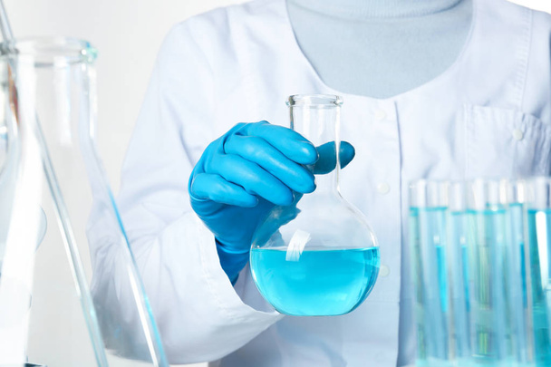 Scientist holding Florence flask with color liquid, closeup. Solution chemistry - Valokuva, kuva