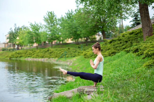 Szczupła brunetka dziewczyna robi jogę w lecie na zielonym trawniku przez t - Zdjęcie, obraz