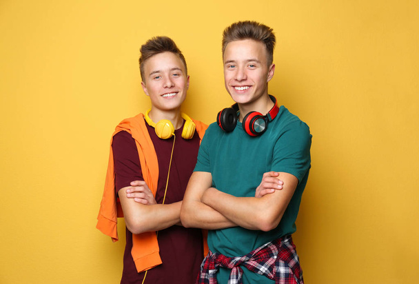 Teenage twin brothers with headphones on color background - Foto, Imagem