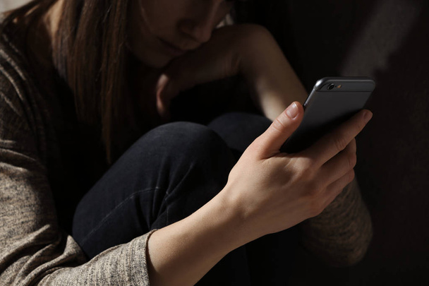Woman using smartphone in dark room, closeup. Loneliness concept - Foto, afbeelding