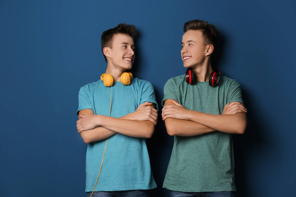 Teenage twin brothers with headphones on color background - Фото, зображення