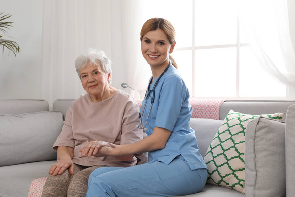 Nurse with elderly woman indoors. Assisting senior people - Foto, imagen