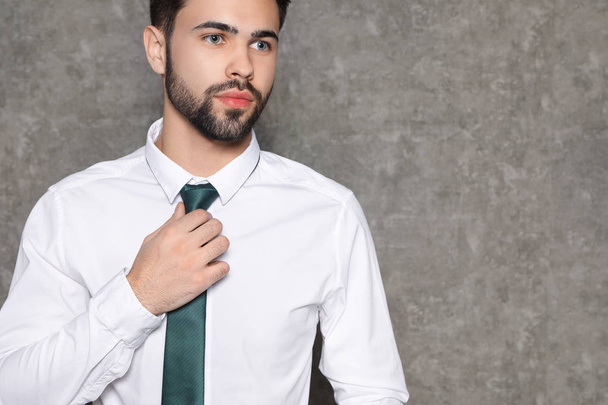Portrait of businessman straightening tie on grey background, closeup. Space for text - Φωτογραφία, εικόνα