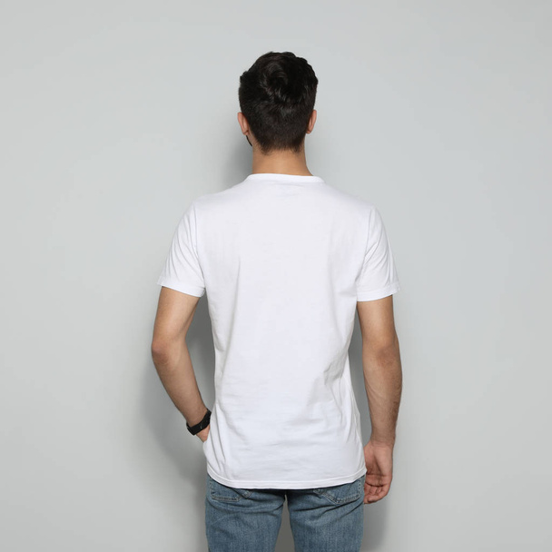 Young man in t-shirt on light background. Mock up for design - Fotó, kép