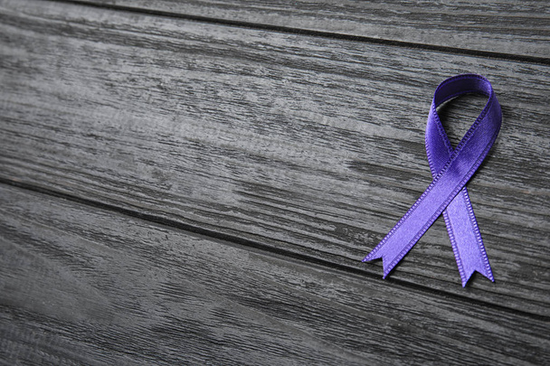 Purple ribbon on grey wooden background, space for text. Domestic violence awareness - Foto, afbeelding