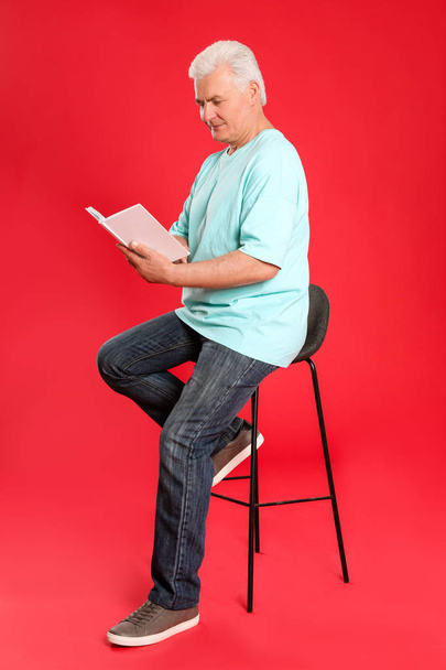Senior man reading book on color background - Фото, зображення