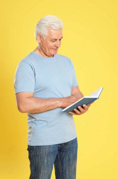 Senior man reading book on color background - Photo, image