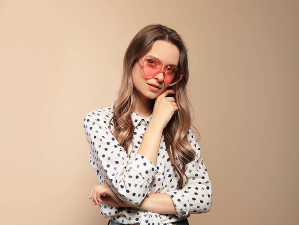 Portrait of beautiful young woman with heart shaped sunglasses on color background - Foto, Imagem