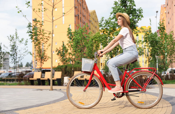 Young pretty woman riding bicycle in city. Space for text - Zdjęcie, obraz