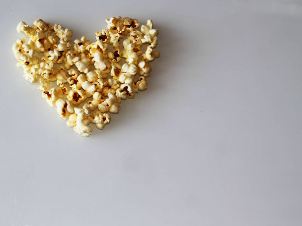 popcorn laid out in the shape of a heart on a white background - Φωτογραφία, εικόνα
