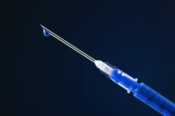 Шприц, наполненный голубым лекарством и капающий с иглы
 - Фото, изображение