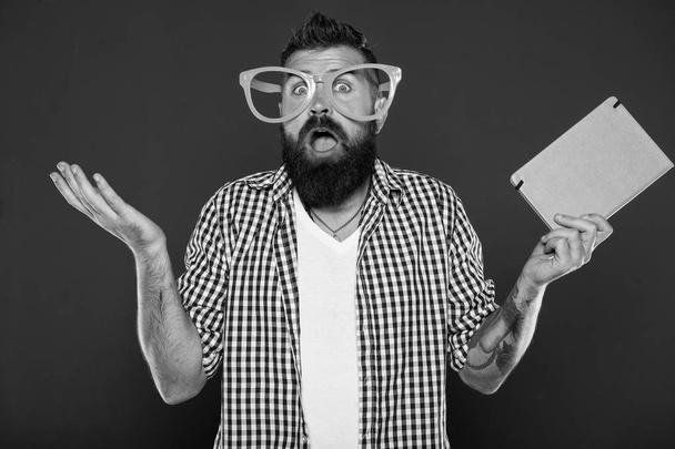 Expressing wonder. Book nerd making a helpless gesture. University male student wearing fancy glasses with lecture notes. Bearded man in party glasses with lesson book. Study nerd holding book - Foto, afbeelding