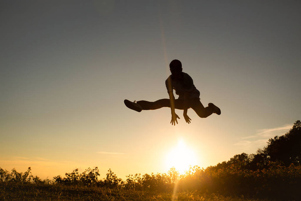 Φιγούρα των ευτυχισμένων ανθρώπων που πηδούν στο ηλιοβασίλεμα στον Μουτέν. - Φωτογραφία, εικόνα