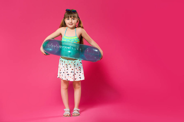 niedliches kleines Mädchen mit aufblasbarem Ring auf farbigem Hintergrund - Foto, Bild