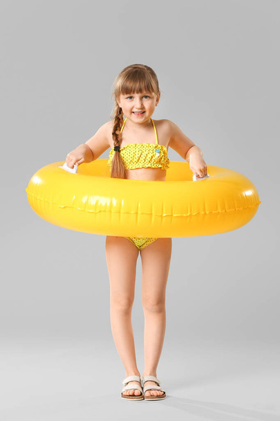Cute little girl with inflatable ring on grey background - Photo, image