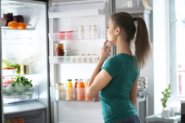 Evde açık buzdolabının yanında duran kadın - Fotoğraf, Görsel