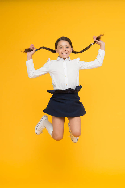 happy child jumping in school uniform. having fun. time for fun. school break. jumping and feeling free. childhood happiness. back to school. first day of study. little girl on yellow background - Zdjęcie, obraz