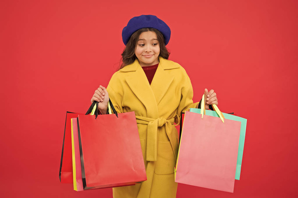 Prime time buy spring clothing. Obsessed with shopping. Girl cute kid hold shopping bags red background. Get discount shopping on birthday holiday. Fashionista adore shopping. Customer satisfaction - Photo, image