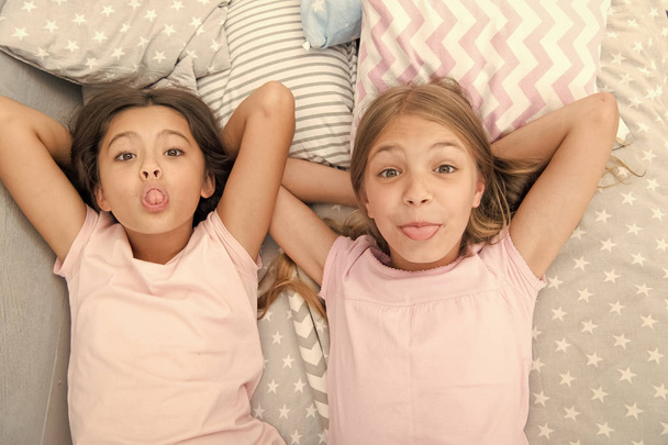 Leisure and fun. Having fun with best friend. Children playful cheerful mood having fun together. Pajama party and friendship. Sisters happy small kids relaxing in bedroom. Friendship of small girls - Photo, image