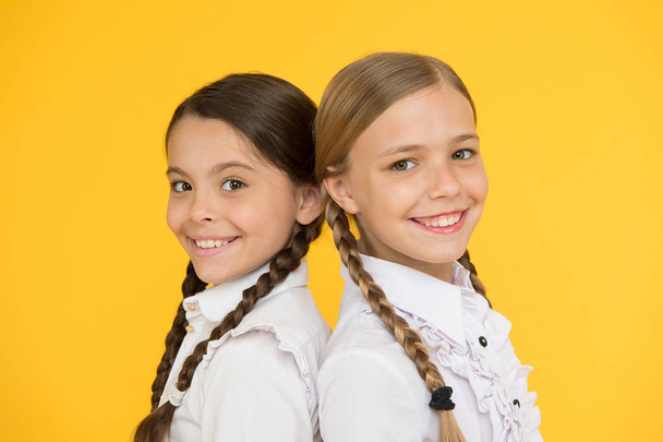 smart and clever. kid formal fashion. Education abroad. smart looking children. school friends. happy children in uniform. little girls on yellow background. friendship and sisterhood. best friends - Photo, image