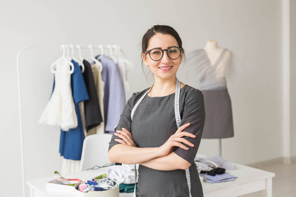 Dressmaker, fashion designer and tailor concept - Young dressmaker woman over clothes rack with dresses background - Foto, Imagem