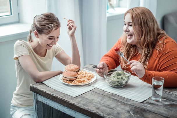Joyeux jeune femme regardant plaque avec des hamburgers
 - Photo, image
