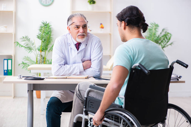 Paciente masculino em cadeira de rodas visitando médico velho
  - Foto, Imagem