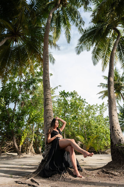 A young girl lay down on a big palm tree with coconuts. - Foto, Imagen