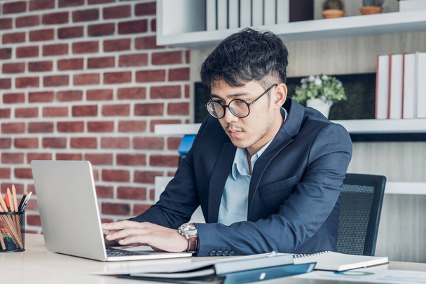 Aasialainen liikemies työskentelee kannettavan tietokoneen toimistossa.
. - Valokuva, kuva