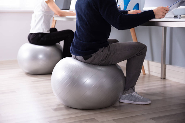 Two Businesspeople Working On Computer In Office Sitting On Fitness Ball - Photo, image