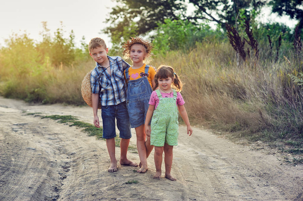 Τα παιδιά σε μια βόλτα στην ύπαιθρο ξυπόλητοι. Ευτυχισμένα παιδιά με βρώμικα πόδια. Σκονισμένος δρόμος του χωριού - Φωτογραφία, εικόνα