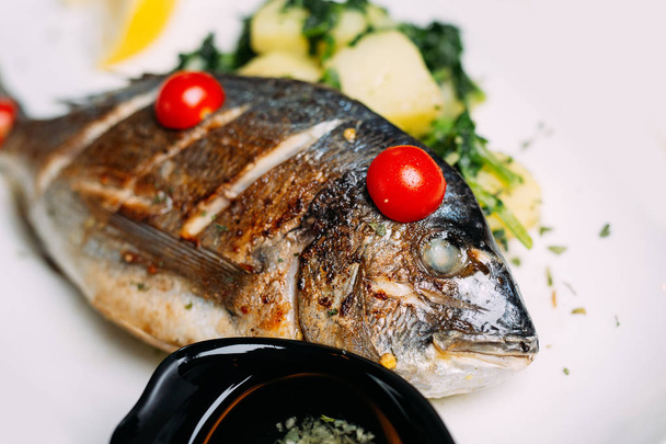 Смажена риба дорадо з овочами на тарілці
 - Фото, зображення