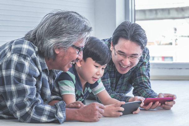 Feliz generación de tres hombres está aprendiendo a usar el teléfono móvil i
 - Foto, Imagen