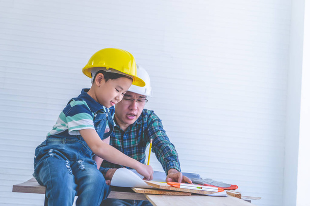 Bauarbeiter-Vater bringt seinem Sohn das Lesen des Bauplans bei - Foto, Bild