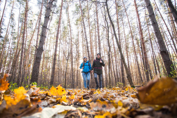aventura, viajes, turismo, senderismo y concepto de personas - pareja sonriente caminando con mochilas sobre fondo natural de otoño
 - Foto, Imagen