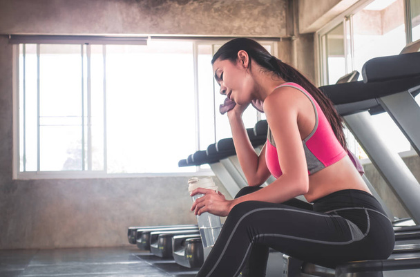 Woman is drinking water on treadmill workout in fitness gym - Fotografie, Obrázek