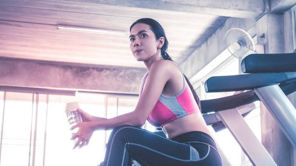 Vrouw drinkt water op loopband workout in fitnessruimte - Foto, afbeelding
