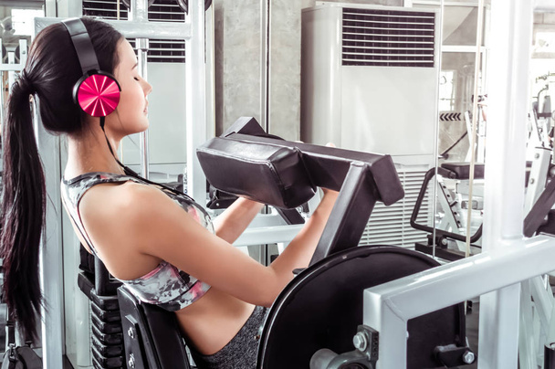 Frau mit rosa Kopfhörer trainiert Bauch in Fitnessgerät - Foto, Bild